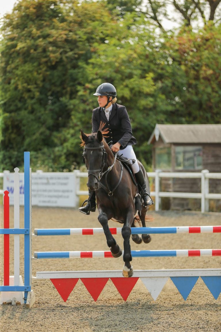 woman showjumper clearing a fence at a competition