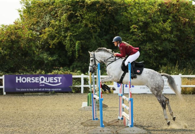 grey horse jumping a competion fence